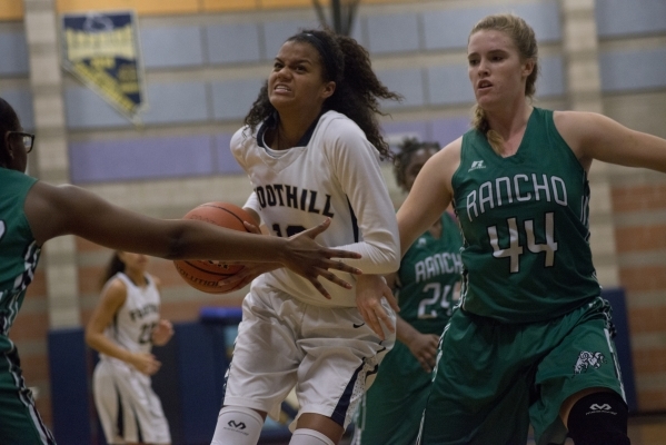 FoothillÃ­s Rae Burrell (12) works the ball toward the basket as Rancho‘s Samantha P ...