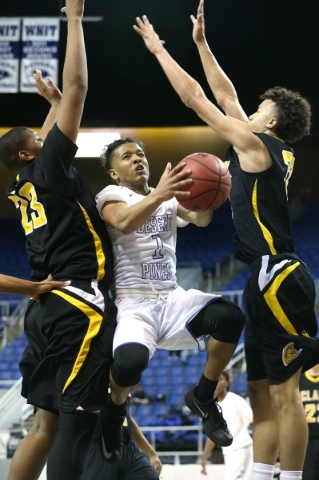 Desert Pines‘ Capri Uzan drives through Clark defenders Antwon Jackson, left, and Ian ...