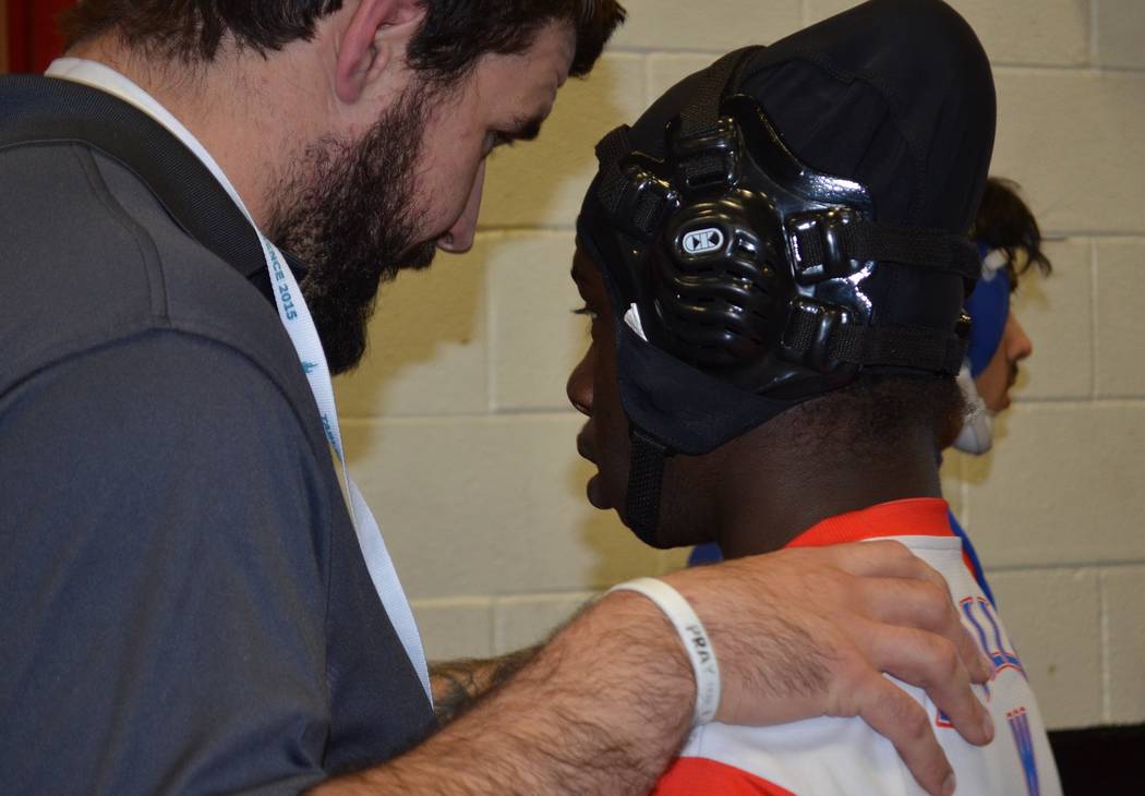 Valley coach Tyler Perry, left, speaks to 145-pounder Xzavier Maheia before a match Friday i ...