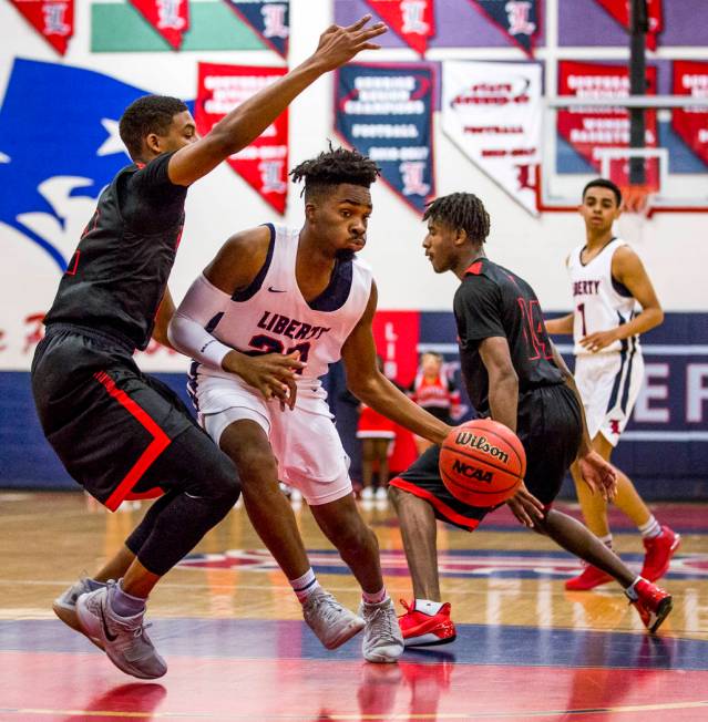 Liberty’s Davion Ware (23) attempts to keep the ball away from Las Vegas defenders Zio ...