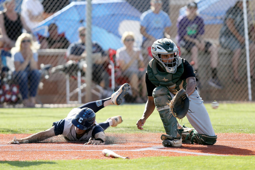 Centennial Zachary Hare (5) slides into home as Palo Verde catcher Jacob Godman (23) fields ...