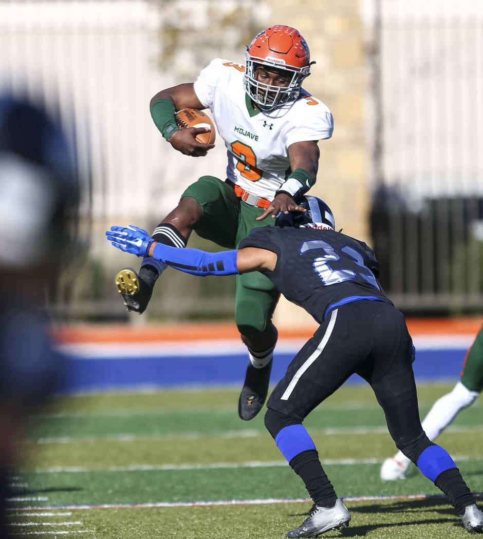 Mojave’s Tawee Walker (3) jumps to avoid a tackle from Desert Pines’ Andrew Will ...