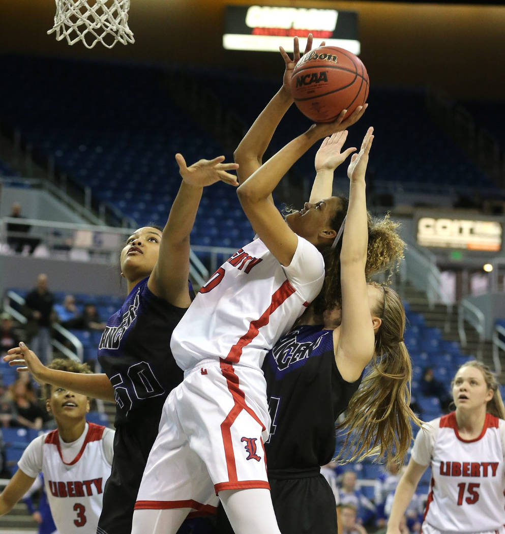 Liberty’s Rae Burrell shoots past McQueen defenders Alisi Peaua and Kendra McAninch d ...