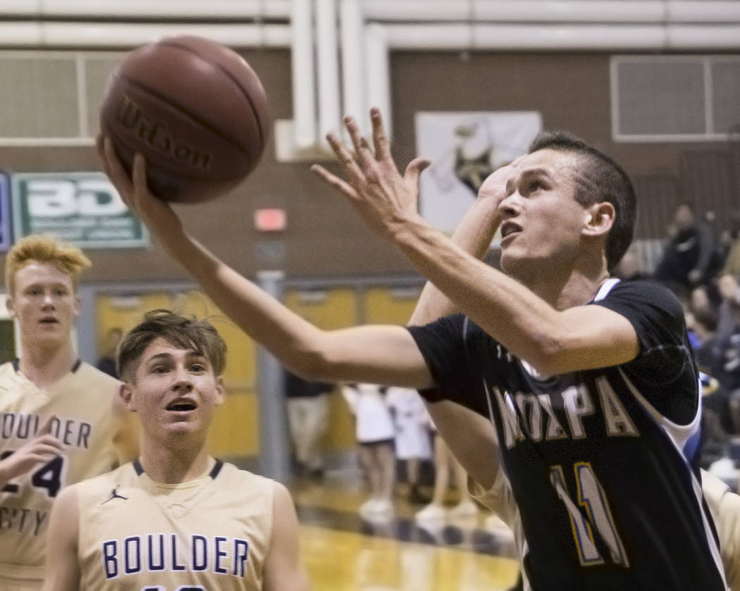 Moapa Valley sophomore guard Lucas Walker (11) drives past Boulder City junior guard Gavin B ...