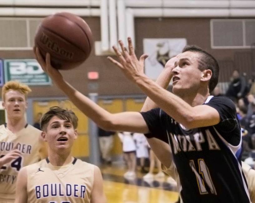 Moapa Valley sophomore guard Lucas Walker (11) drives past Boulder City junior guard Gavin B ...