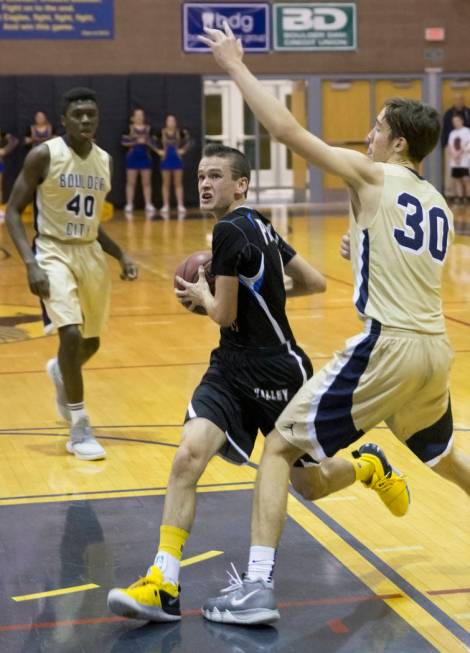 Moapa Valley sophomore guard Lucas Walker (11) drives past Boulder City sophomore forward Et ...