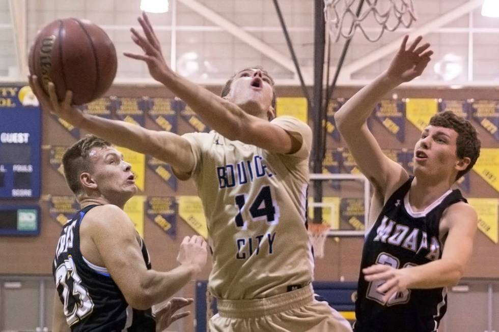 Boulder City senior guard Karson Bailey (14) slices to the rim past Moapa Valley sophomore f ...