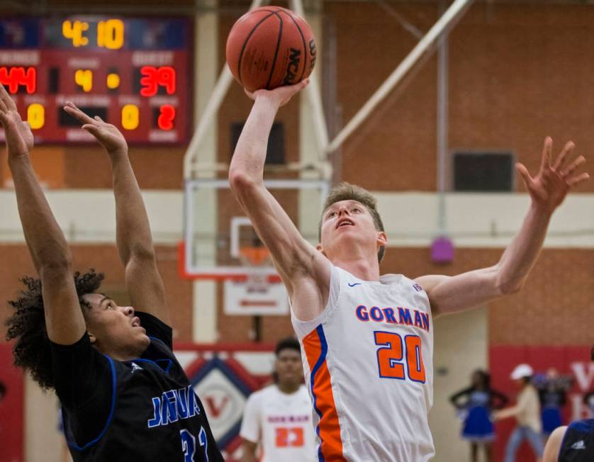 Bishop Gorman senior guard Noah Taitz (20) drives past Desert Pines freshman Jamir Stephens ...