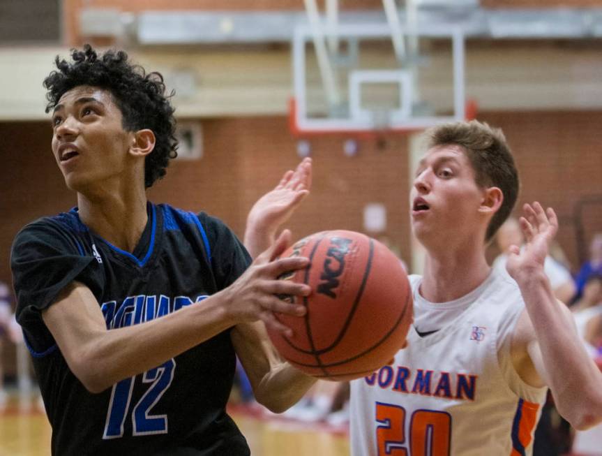 Desert Pines freshman Milos Uzan (12) drives past Bishop Gorman senior guard Noah Taitz (20) ...