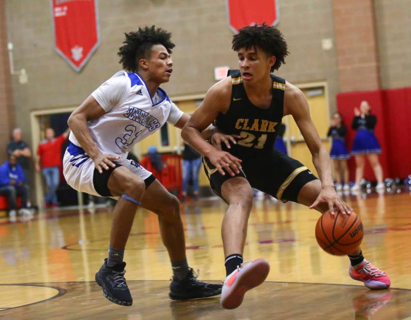 Clark’s Jalen Hill (21) moves the ball around Desert Pines’ Jamir Stephens (33) ...