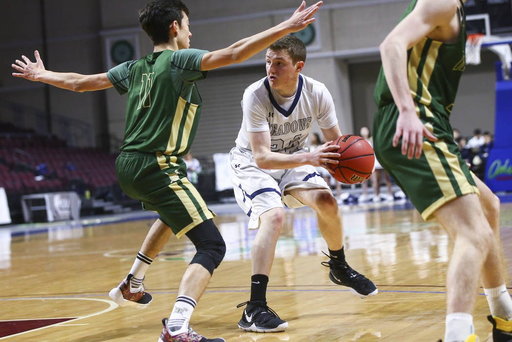 The Meadows guard Allen Fridman (24) moves the ball around Incline guard Johnny Redfern (11) ...