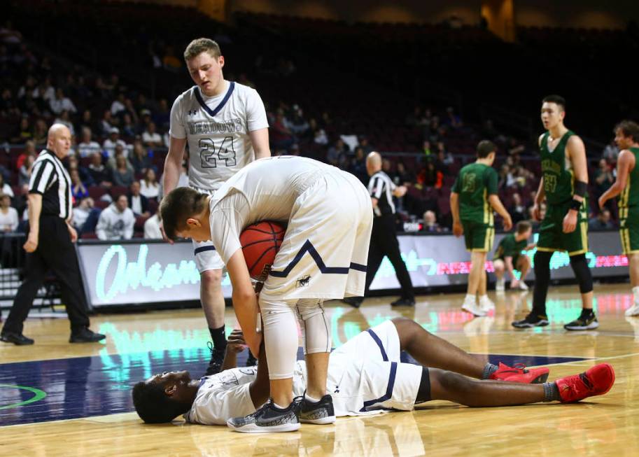 The Meadows guard Allen Fridman (24) and Trey Covell (5) check on teammate Obinna Ezeanolue ...