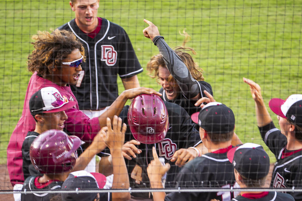 Desert Oasis players congratulate Parker Schmidt (4), center, on another run against Reno d ...