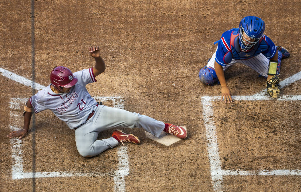 Desert Oasis runner Jacob Walsh (21) slides home safely past Reno catcher Lane Oliphant (28) ...