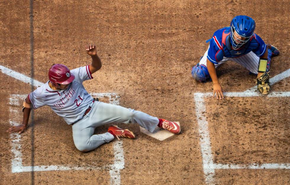 Desert Oasis runner Jacob Walsh (21) slides home safely past Reno catcher Lane Oliphant (28) ...