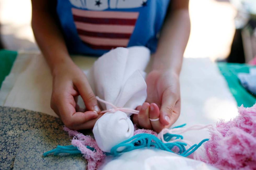 An attendee of Pioneer Day experiences life as a pioneer while making a pin doll at Old Mormon ...