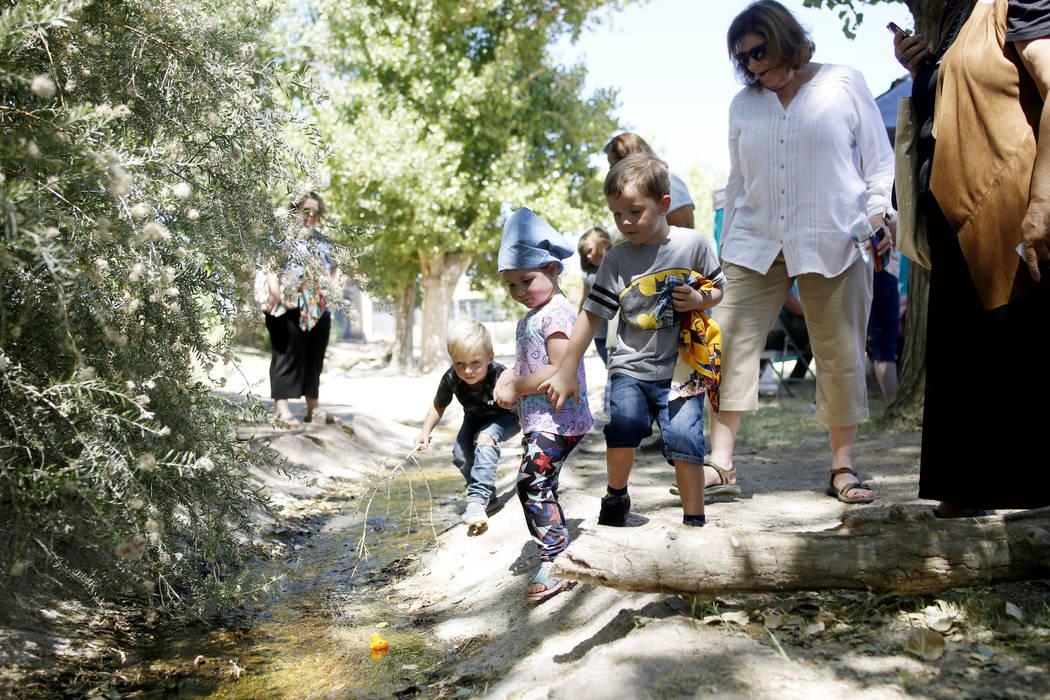 Children watch their plastic ducks used in a duck race float down a river during Pioneer Day at ...