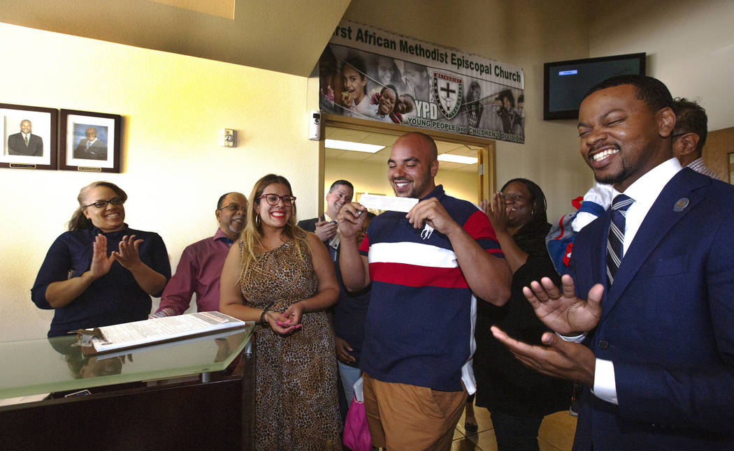 Jovan Jackson, 27, center, holds up his voter ID after signing the paperwork to register to vot ...