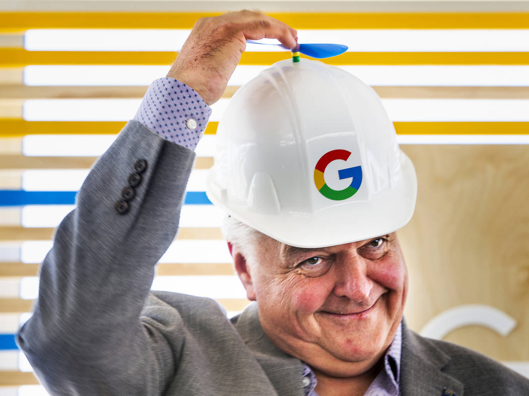 Gov. Steve Sisolak spins the little propeller atop his Google hard hat before a ceremonial dirt ...