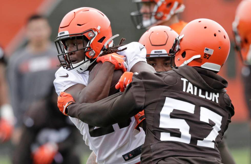 Cleveland Browns running back Kareem Hunt, left, breaks a tackle by linebacker Adarius Taylor d ...