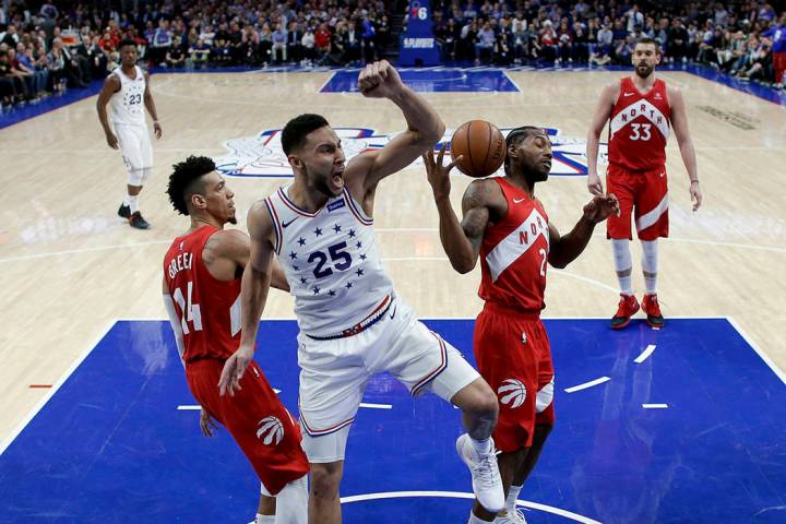 Philadelphia 76ers' Ben Simmons (25) reacts after dunking the ball between Toronto Raptors' Dan ...