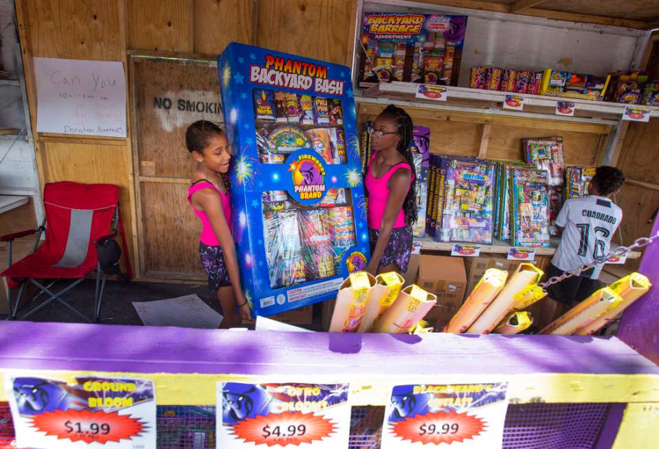 Ava Jordan, 11, left, and her sister Isaiah Jordan, right, 14, help move a box of fireworks whi ...