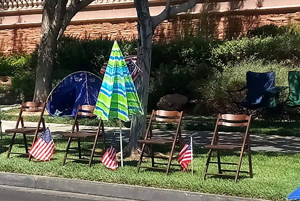 Wooden chairs, an umbrella and U.S. flags mark the spot where a family will watch the 25th annu ...