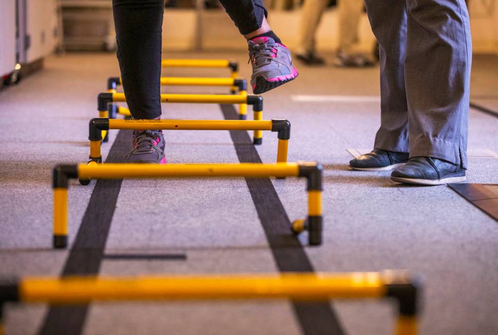 A patient steps over small hurdles within the physical therapy department at the Cleveland Clin ...