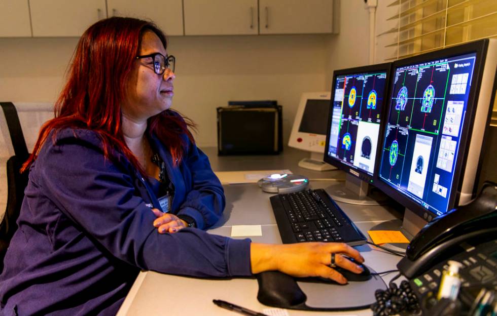 Technologist Vanessa Martinez operates a positron emission tomography (PET) scan for a patient ...