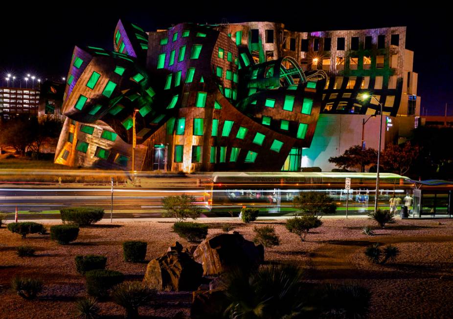 The windows are bathed in green from within the Keep Memory Alive Event Center designed by reno ...