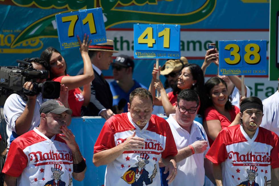 Geoffrey Esper, left, Joey Chestnut, center, and Matt Stone finish the men's competition of Nat ...