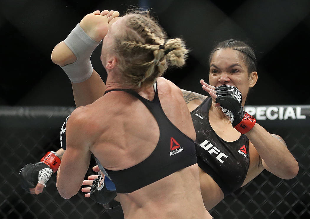 Amanda Nunes, right, connects with a high kick against Holly Holm in the first round during the ...