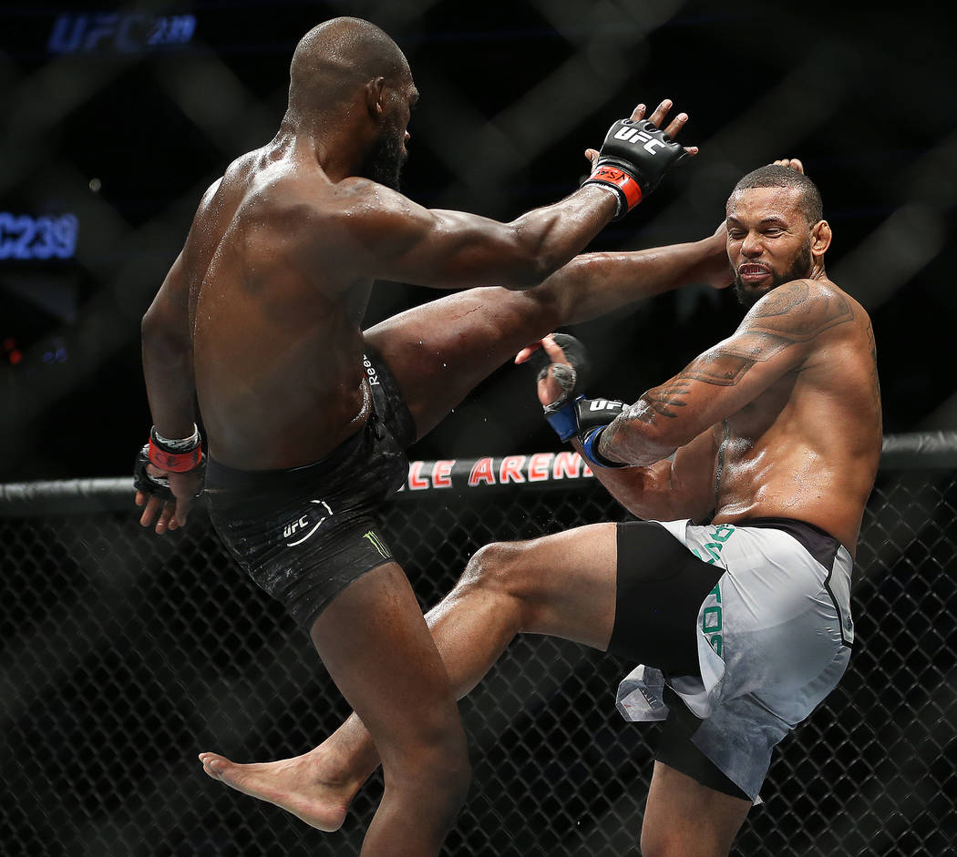 Jon Jones, left, lands a high kick against Thiago Santos in the first round during their light ...