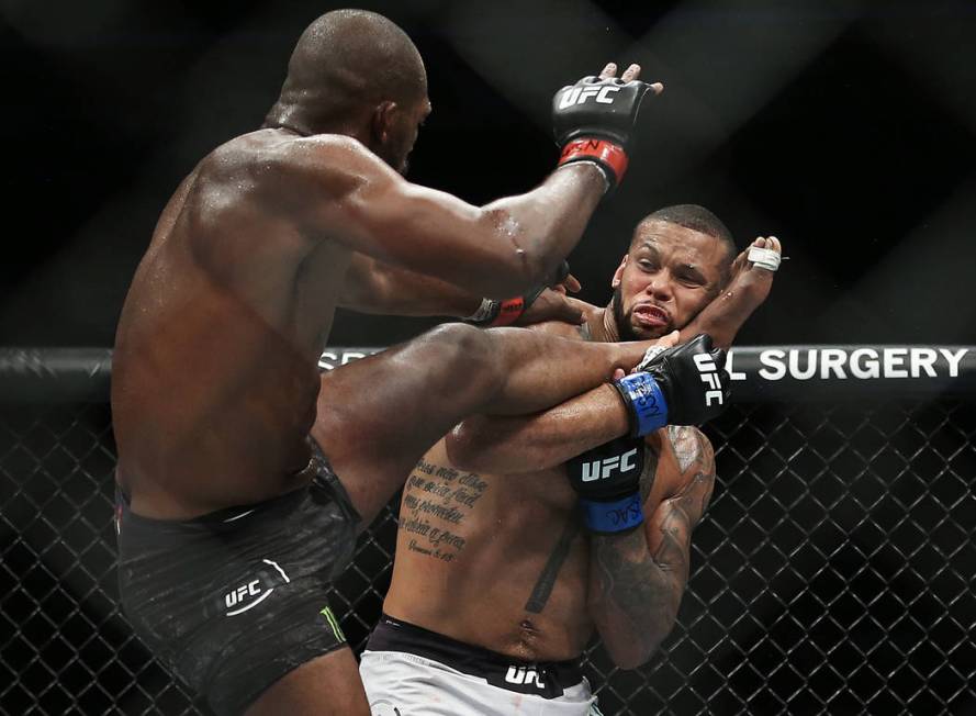 Jon Jones, left, lands a high kick against Thiago Santos in the third round during their light ...