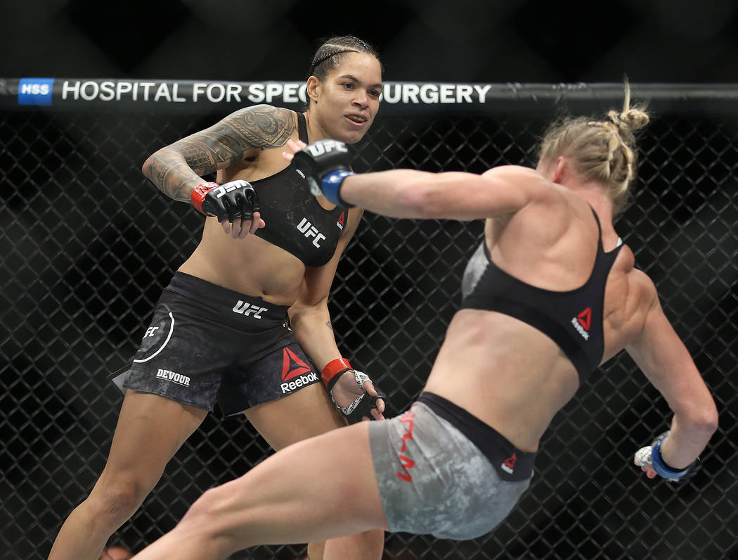 Amanda Nunes, left, watches Holly Holm fall after connecting with a high kick in the first roun ...