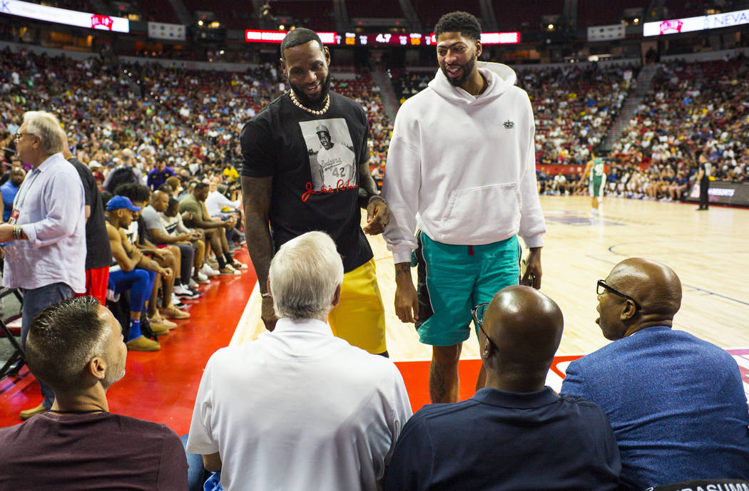 Los Angeles Lakers' LeBron James and Anthony Davis talk with Jerry West, of the Clippers, seate ...