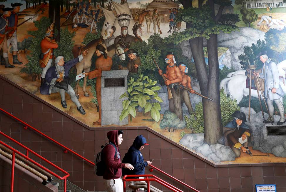 In this photo taken April 3, 2019, a pair of students walk past a historic mural that includes ...