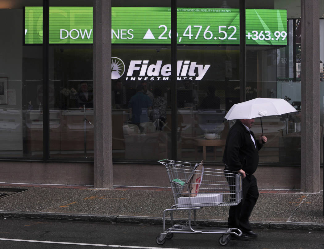 In this June 18, 2019, photo a man pulls a grocery cart as he walks in the rain past the stock ...