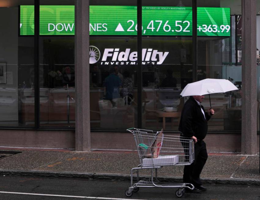 In this June 18, 2019, photo a man pulls a grocery cart as he walks in the rain past the stock ...