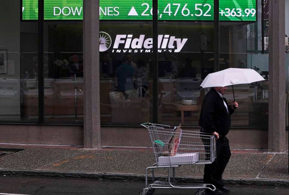 In a June 18, 2019, photo a man pulls a grocery cart as he walks in the rain past the stock tic ...