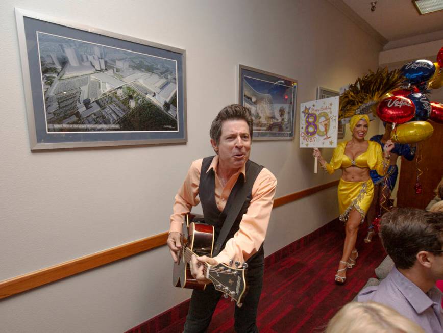 Elvis Impersonator Gregg Peterson plays guitar as showgirl Jennifer Gagliano, background,& ...