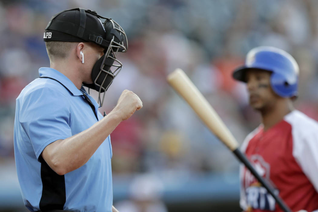 Home plate umpire Brian deBrauwere, left, calls a strike given to him by a radar system over an ...