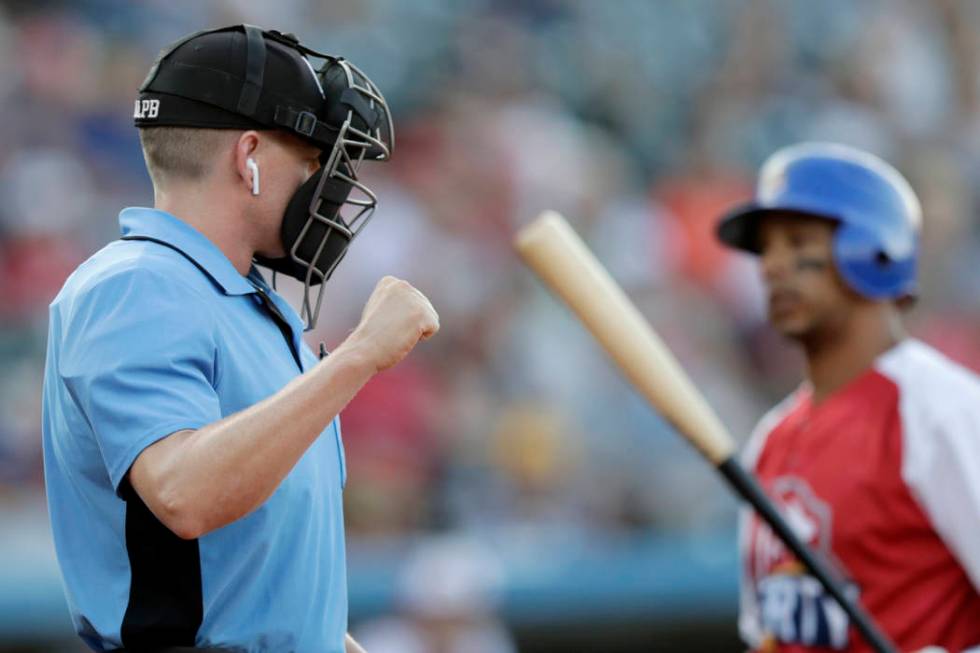 Home plate umpire Brian deBrauwere, left, calls a strike given to him by a radar system over an ...