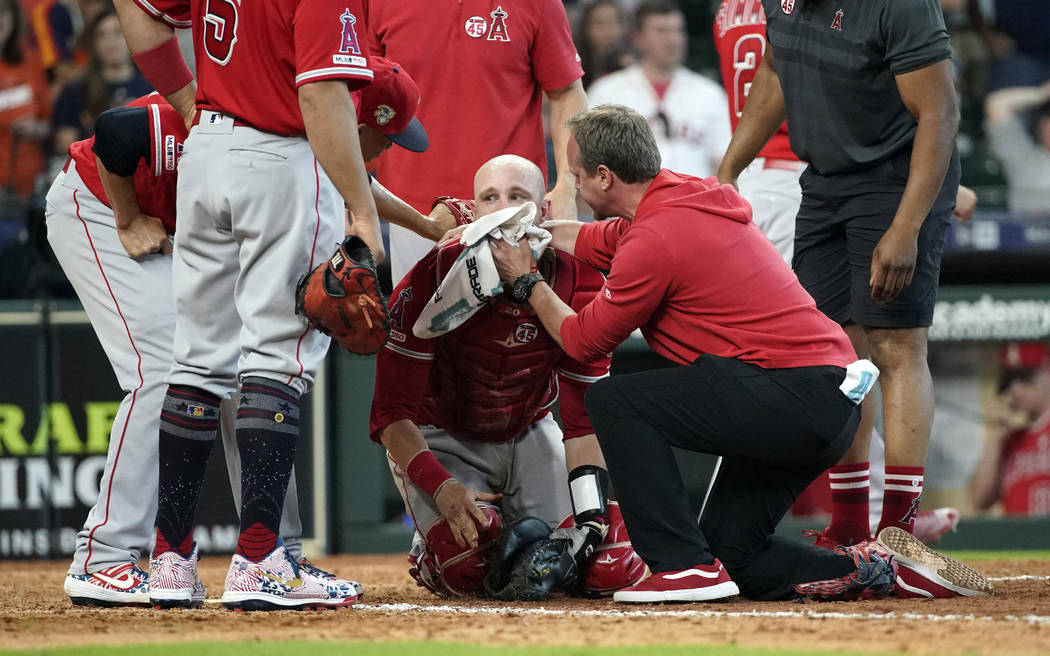 Los Angeles Angels' Jonathan Lucroy, center, is helped by medical personnel after colliding wit ...