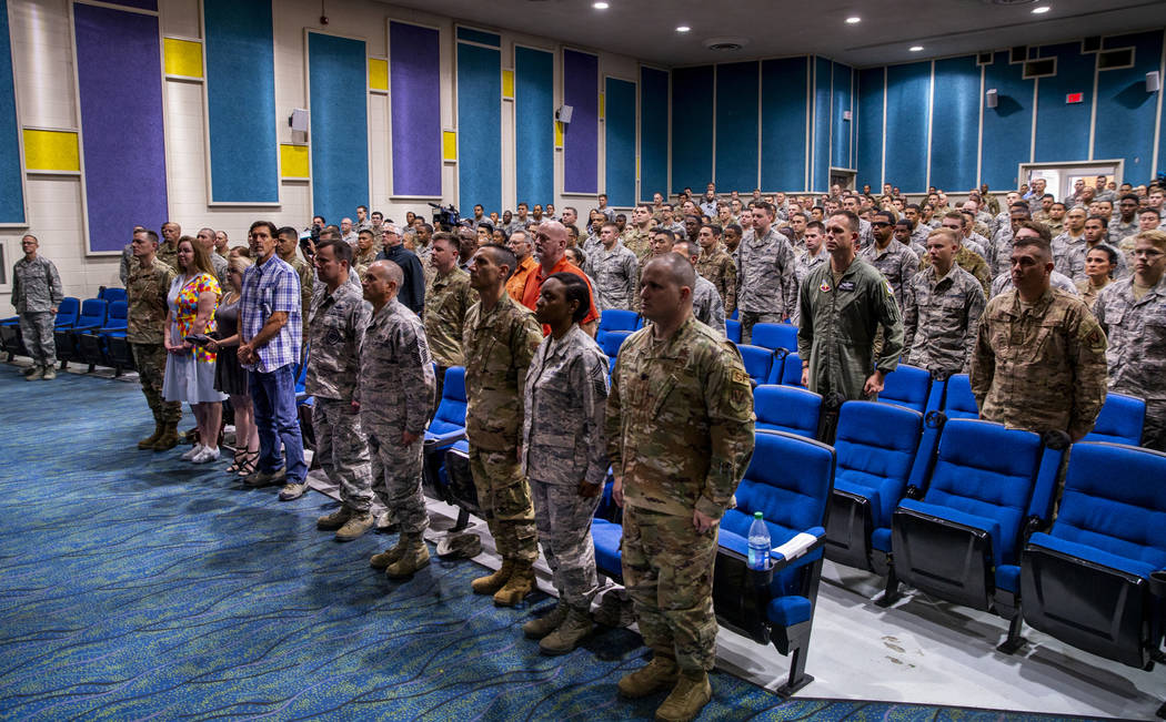 Family, friends and invited guests stand on behalf of Staff Sgt. Kenneth DeLongchamp during the ...