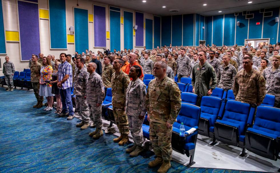 Family, friends and invited guests stand on behalf of Staff Sgt. Kenneth DeLongchamp during the ...