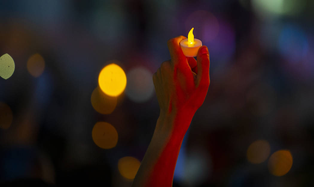 Advocates, activists and impacted persons hold lit candles and yell protest chants during Light ...