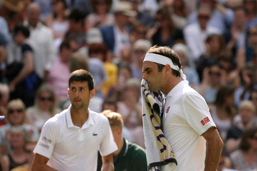 Switzerland's Roger Federer wipes his face after losing a set to Serbia's Novak Djokovic, left, ...