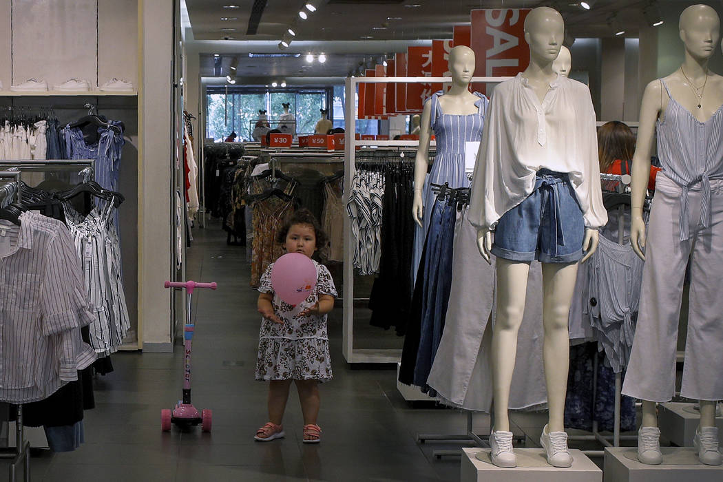 A child plays with a balloon at a clothing store having a promotion sale in Beijing, Monday, Ju ...