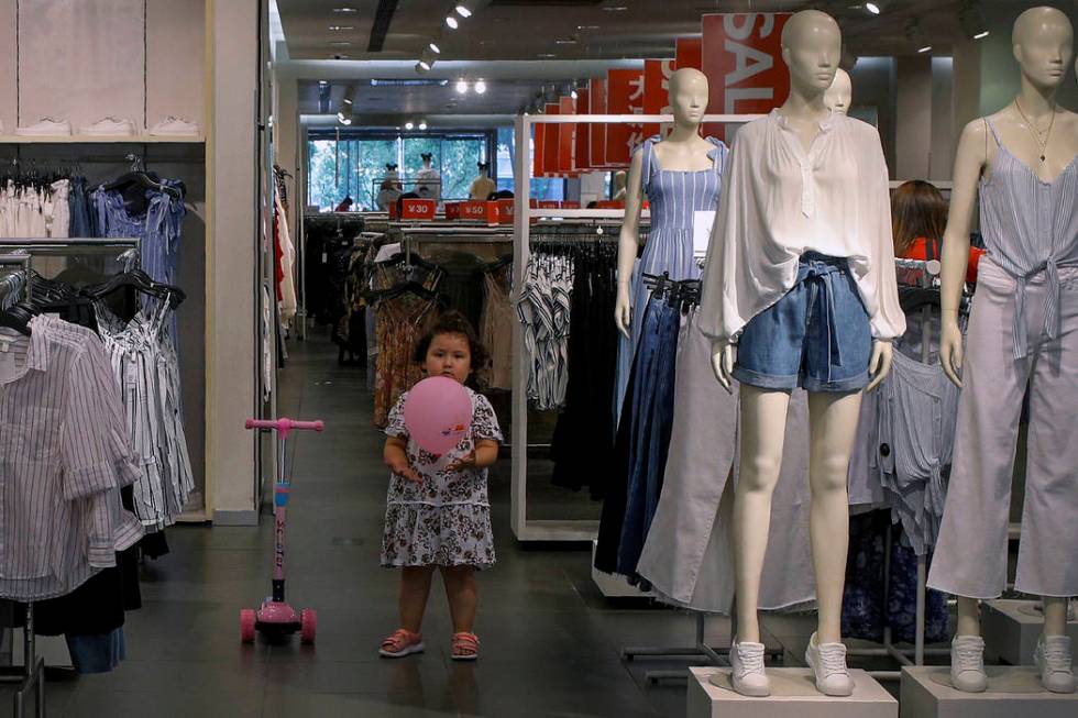 A child plays with a balloon at a clothing store having a promotion sale in Beijing, Monday, Ju ...